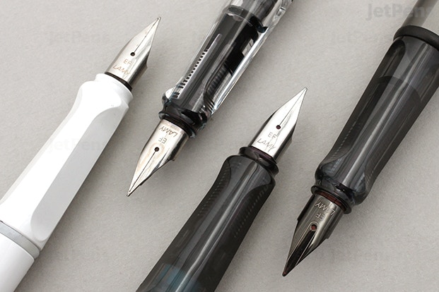 Black, white, and clear Lamy Safari pens laid next to each other, closely cropped so that you can distinguish two grooves in the front of the pen where your fingers go