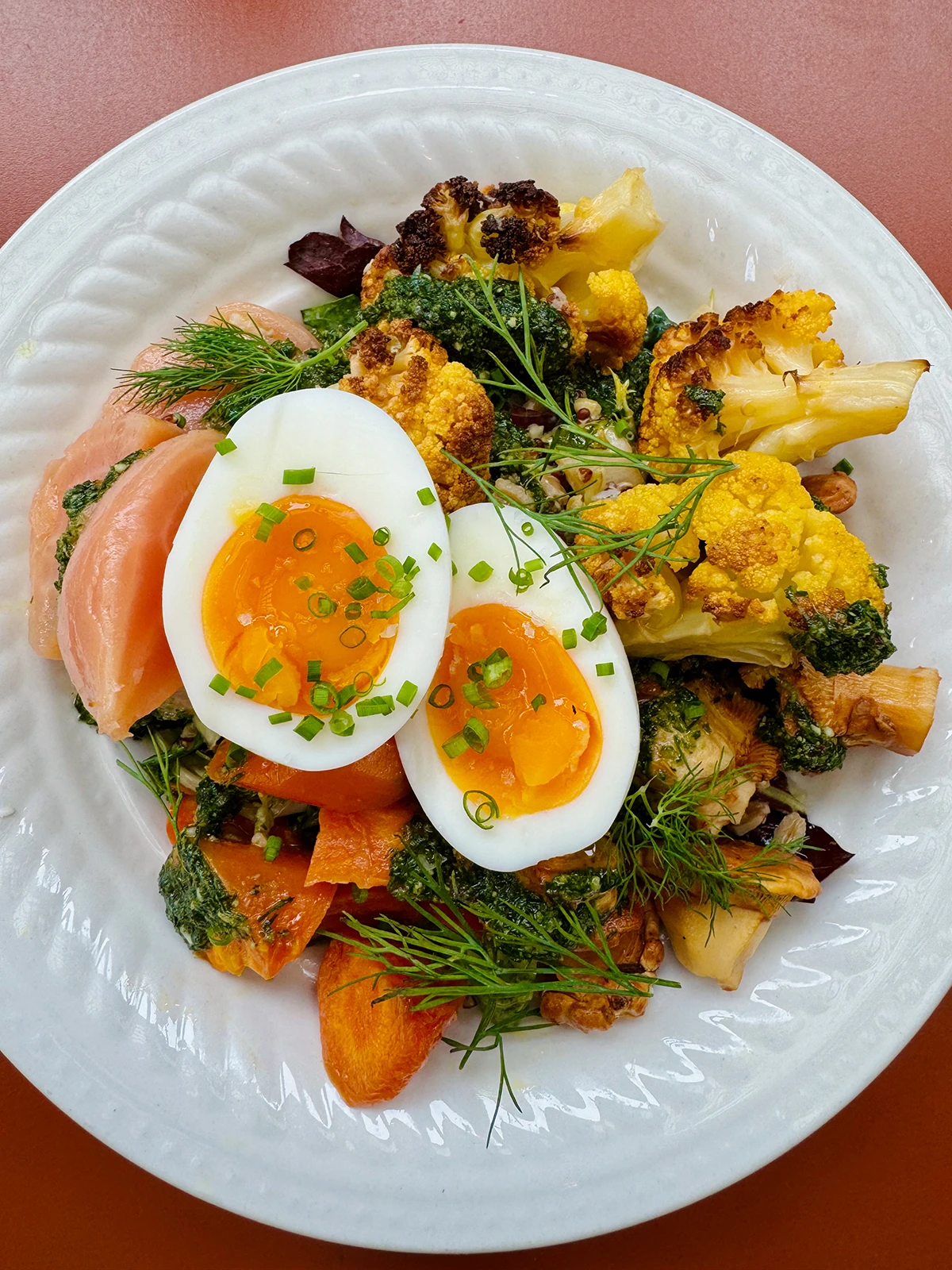 A grain bowl with cauliflower, root veg, and a halved soft boiled egg on top. Lots of color in this meal!