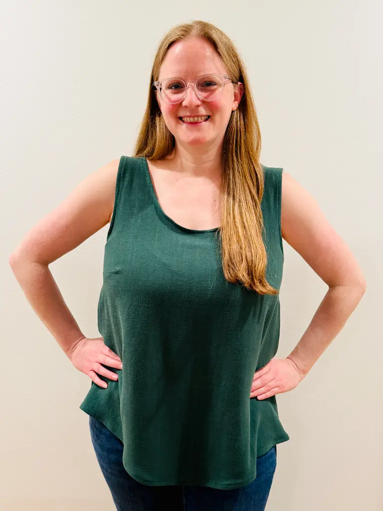 Me smiling in a dark forest green tank top made of a linen-like but somewhat drapier fabric. The surface of the fabric has a little bit of a nubby texture