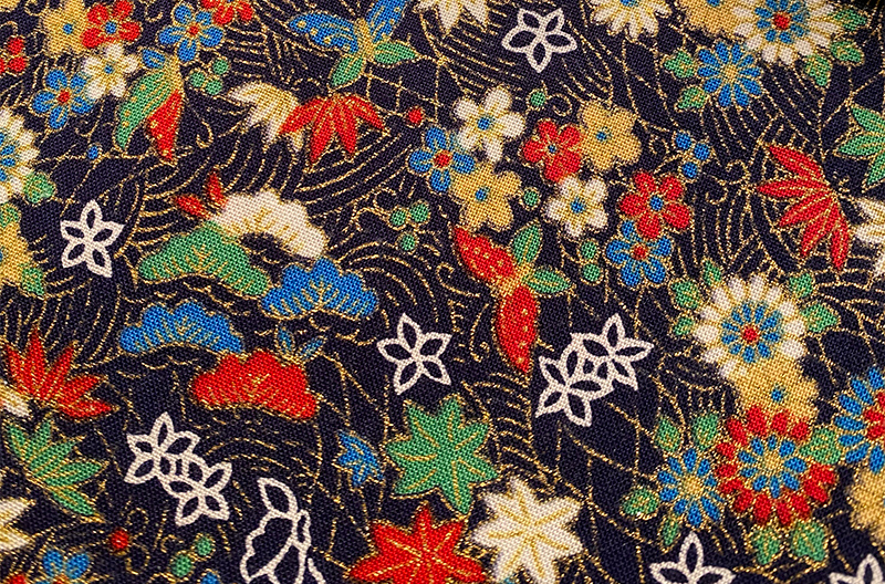 Gilded, floral Japanese fabric. Between the various blossoms float some butterflies.