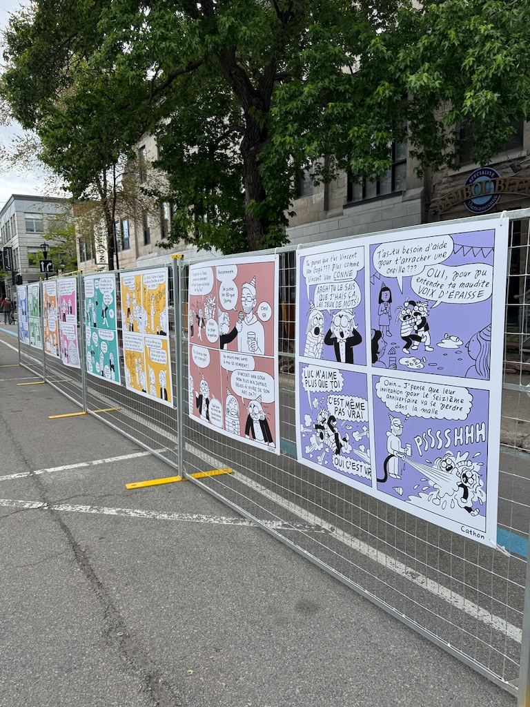 A set of comic panels blown up to poster size, displayed on standing metal grates, sort of like gridded fences or barriers. Each panel is in black and white with an accent background color, and I have no idea what's going on because it's all in French.
