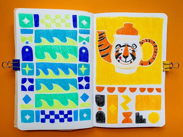 Left sketchbook page: a quilt like grid of abstract shapes in blue and teal, include some shapes like waves. Right page: a teapot with a tiger’s yum face. The spout and handle have a tiger pattern. Underneath are shapes in orange, yellow, and charcoal.